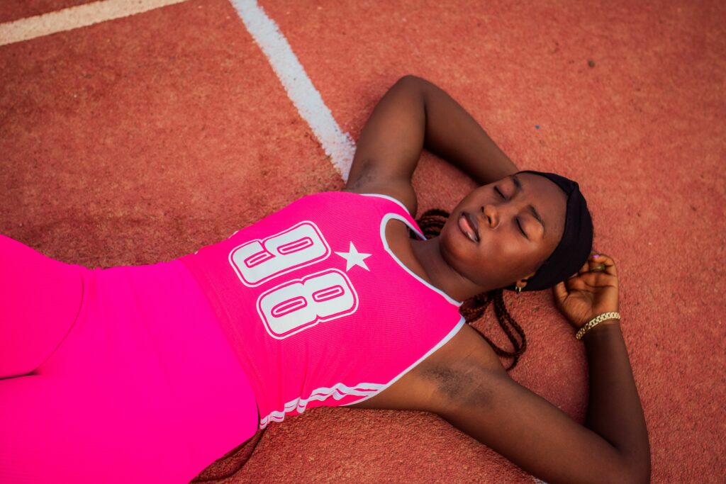 Athlète allongée sur une piste d'athlétisme en phase de récupération après l'effort.