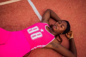 Athlète allongée sur une piste d'athlétisme en phase de récupération après l'effort.